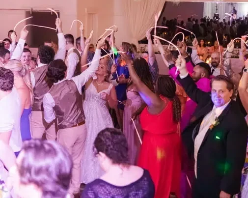 Bride and guests waving glowsticks on a packed dance floor at Venue 111 Holly