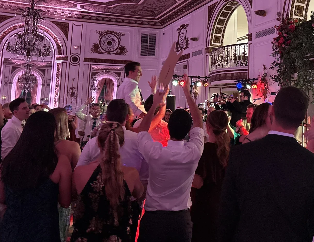 Groom crowd surfing over a packed dance floor at The Colony Club Detroit wedding reception
